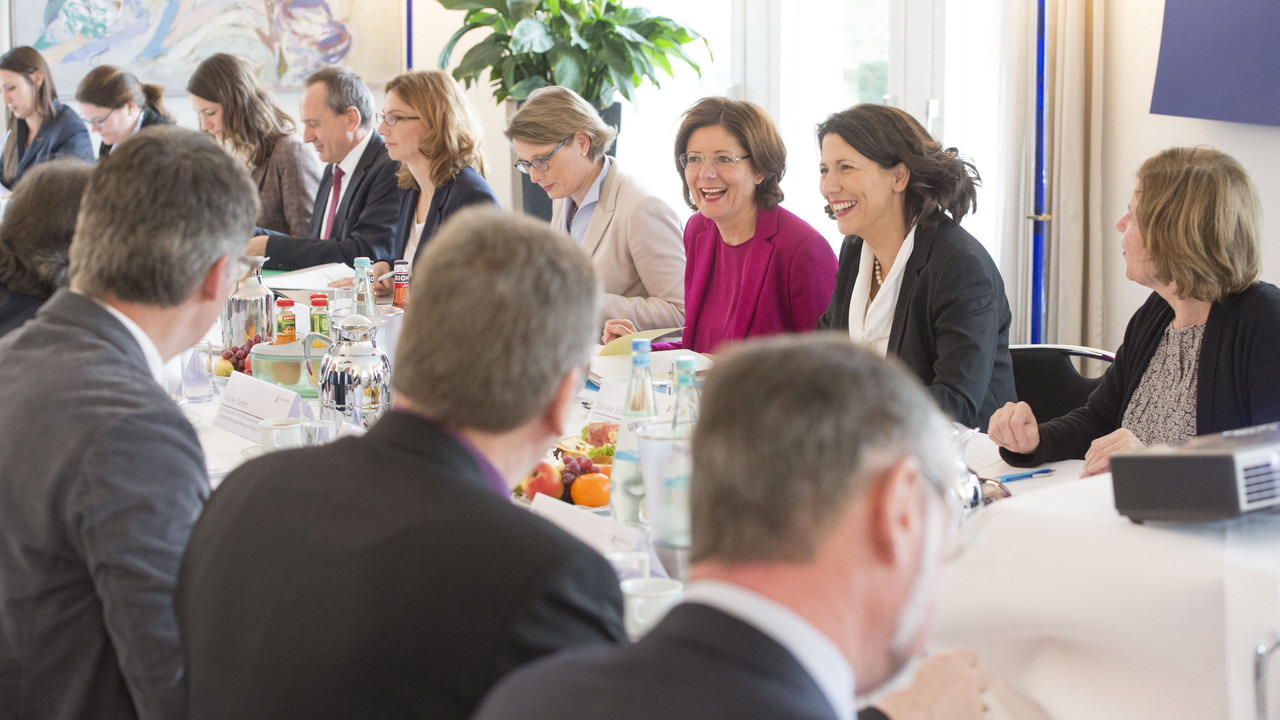 Die Teilnehmerinnen und Teilnehmer des Ovalen Tisches sitzen im Gästehaus der Landesregierung an einem Tisch zusammen